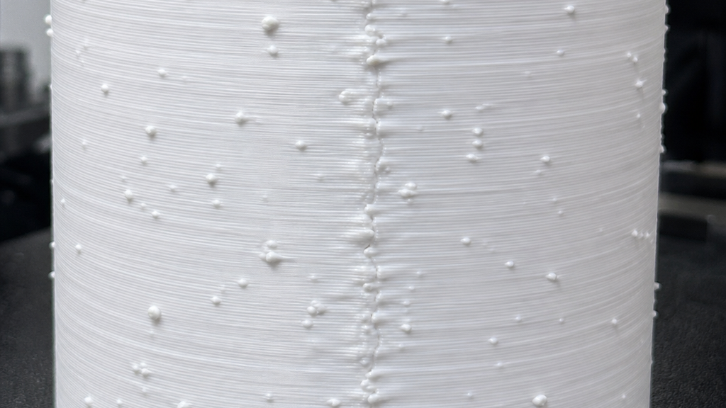 Close-up of a white printed cylinder with scattered bumps and a raised vertical seam.
