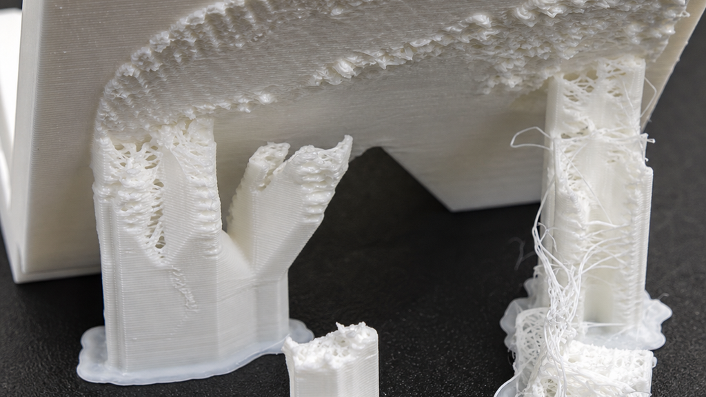 White printed part with collapsed, torn support columns and a damaged supported underside.
